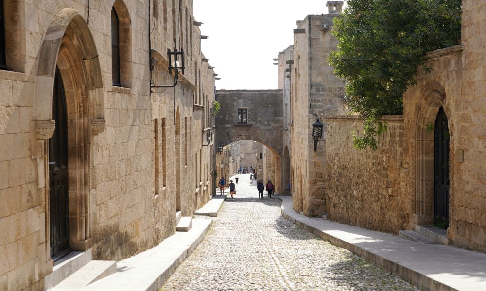 5. See the street of the Knights
Located in the Medieval Town, Street of the Knights is one of the top attractions in Rhodes for both its historical and cultural value. This cobblestone street connects to the Palace of Grand Master and has an amazing view of the Old Town. The street was named as such because it is where the knights used to live at one time. You can still see some buildings that have been preserved from those times today.
Also, this place is filled with medieval houses, museums, restaurants, cafes, souvenir shops, bars and much more. The way this part of the city is designed makes you feel like you are walking in an open-air museum. This makes it a perfect place to relax during a hot summer day or a cold winter night.
I loved walking around this charming alley during my tour here. It has an old-fashioned feel without being too touristy or crowded. Thus, it is very relaxing and calming.

