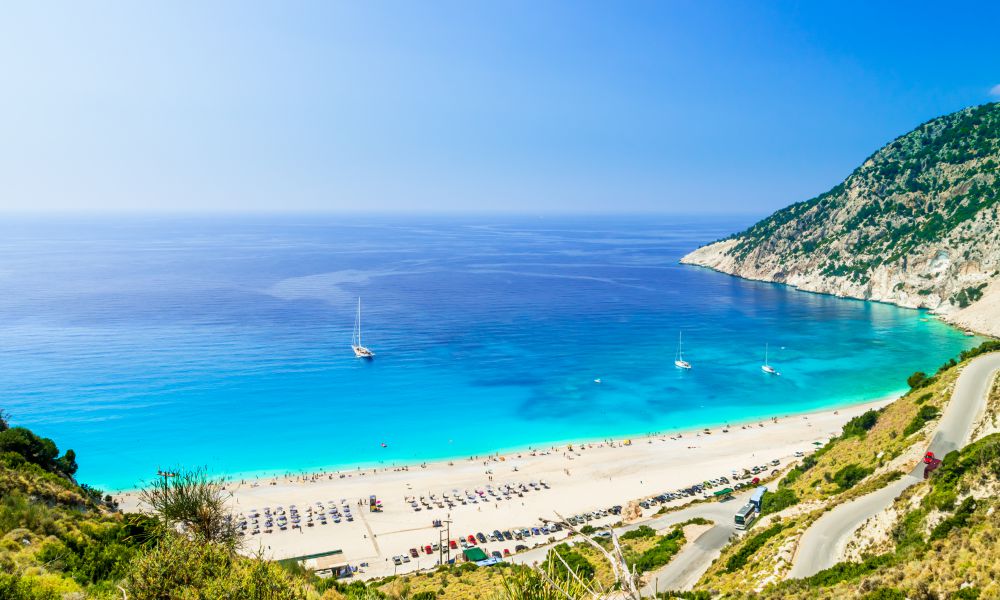 10. Myrtos Beach
A visit to Kefalonia would not be complete without a trip to the beautiful Myrtos Beach. This is a massive stretch of fine white sand, which is also claimed by the beautiful blue waters of the Ionian Sea. The beach has been voted the best in Greece, and it isn't difficult to see why after a visit here.
Visitors flock from all over the world to swim in the shallow crystal clear waters, ideal for families. Take time to explore the beach, which is 2-kilometers in length and a popular destination for walkers. You can find a number of taverns and bars close to the beach, where you can get a cold beer and something to eat. 
I spent the whole day relaxing on the beach and enjoying the wonderful views. And since this is one of the top attractions in Kefalonia, you will usually find a crowd here. So it is best to get here early if you want a choice of sunbeds.

