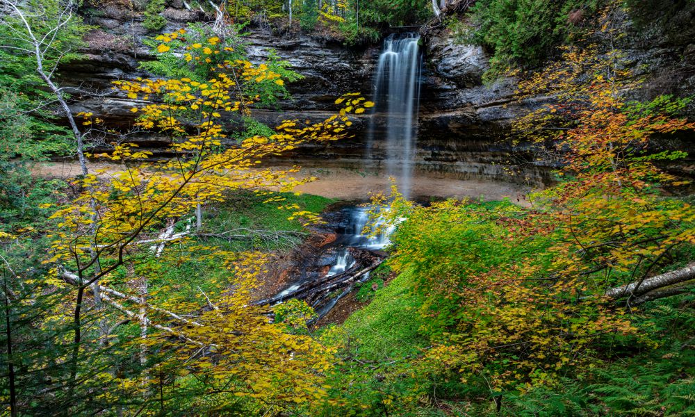 4. Munising Falls
Another one of the best waterfalls in Michigan is Munising Falls, located in the Pictured Rocks National Lakeshore. This is one of the most visited waterfalls in Michigan because it's easily accessible from the road. The falls are only about a 10-minute walk from the parking lot.
This fall plunges 50 feet over a curved rock wall into a large pool at the bottom, which flows into a creek with moss-covered stones. During winter, this waterfall can freeze into dramatic ice sculptures. So if you're visiting in winter, be sure to bundle up!
Things to do near Munising Falls: Since you're already in the Pictured Rocks National Lakeshore, explore some of the other amazing sites in the park. Check out Miners Castle, a rock formation on the shore of Lake Superior, or the Grand Sable Dunes, towering dunes that offer great views of the lake.
